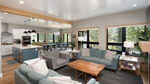 A spacious living area with a kitchen, dining area, and large windows offering views of the outdoors.