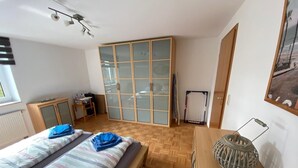 Un dormitorio con dos camas, un armario, un escritorio y una silla.