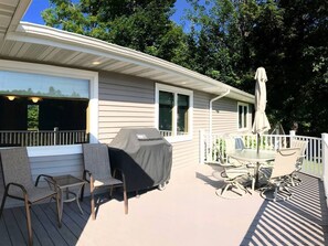 Enjoy al fresco dining on the covered deck with a grill, two chairs, and a table under a shaded umbrella.
