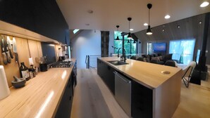 A modern kitchen with a central island, built-in appliances, and pendant lighting. - This deluxe modern new 3-story home with central AC offers the best of Bozeman! (Bozeman)