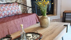 A wooden coffee table with a glass tray, a vase with yellow flowers, and a fireplace in the background.