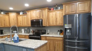 A kitchen with wooden cabinets, a stainless steel refrigerator, a microwave, and a granite countertop. - Black Hills MOJO, come and enjoy the beautiful Nemo area in the Northern Hills. (Nemo)