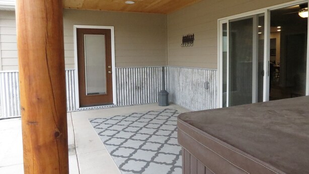A covered porch with a wooden ceiling, a door, and a patterned rug. - Black Hills MOJO, come and enjoy the beautiful Nemo area in the Northern Hills. (Nemo)