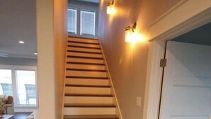 Una escalera con peldaños de madera y una puerta blanca al final.