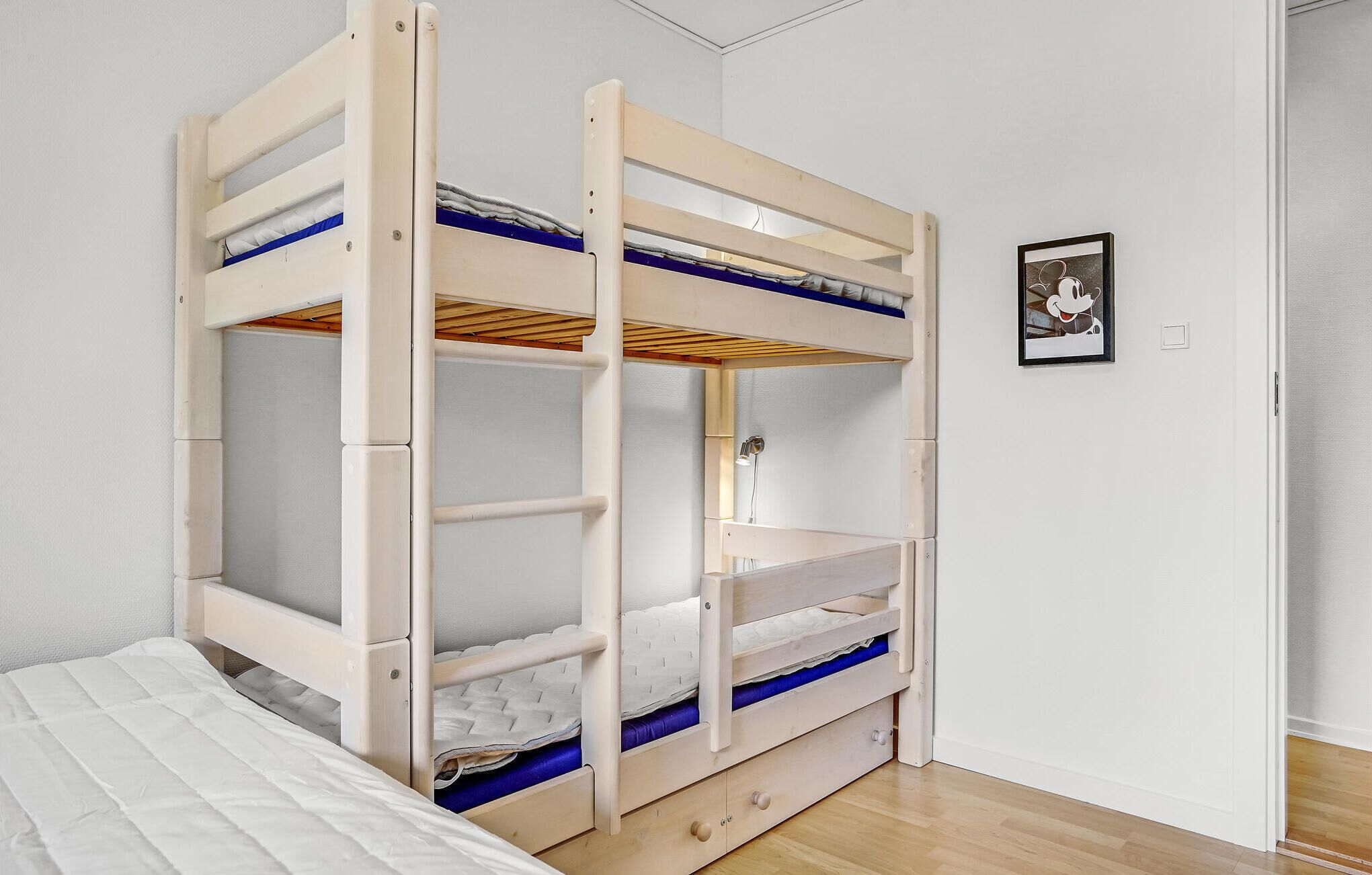 A bunk bed with a storage drawer and a single bed at the bottom.