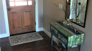 A wooden door with a glass panel, a console table with decorative items, and a large mirror on the wall.