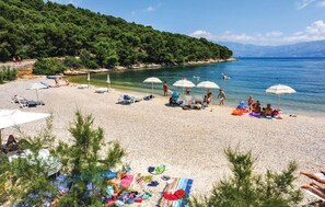 A beach with clear waters, umbrellas, and people. - Beautiful home in Supetar (Supetar)