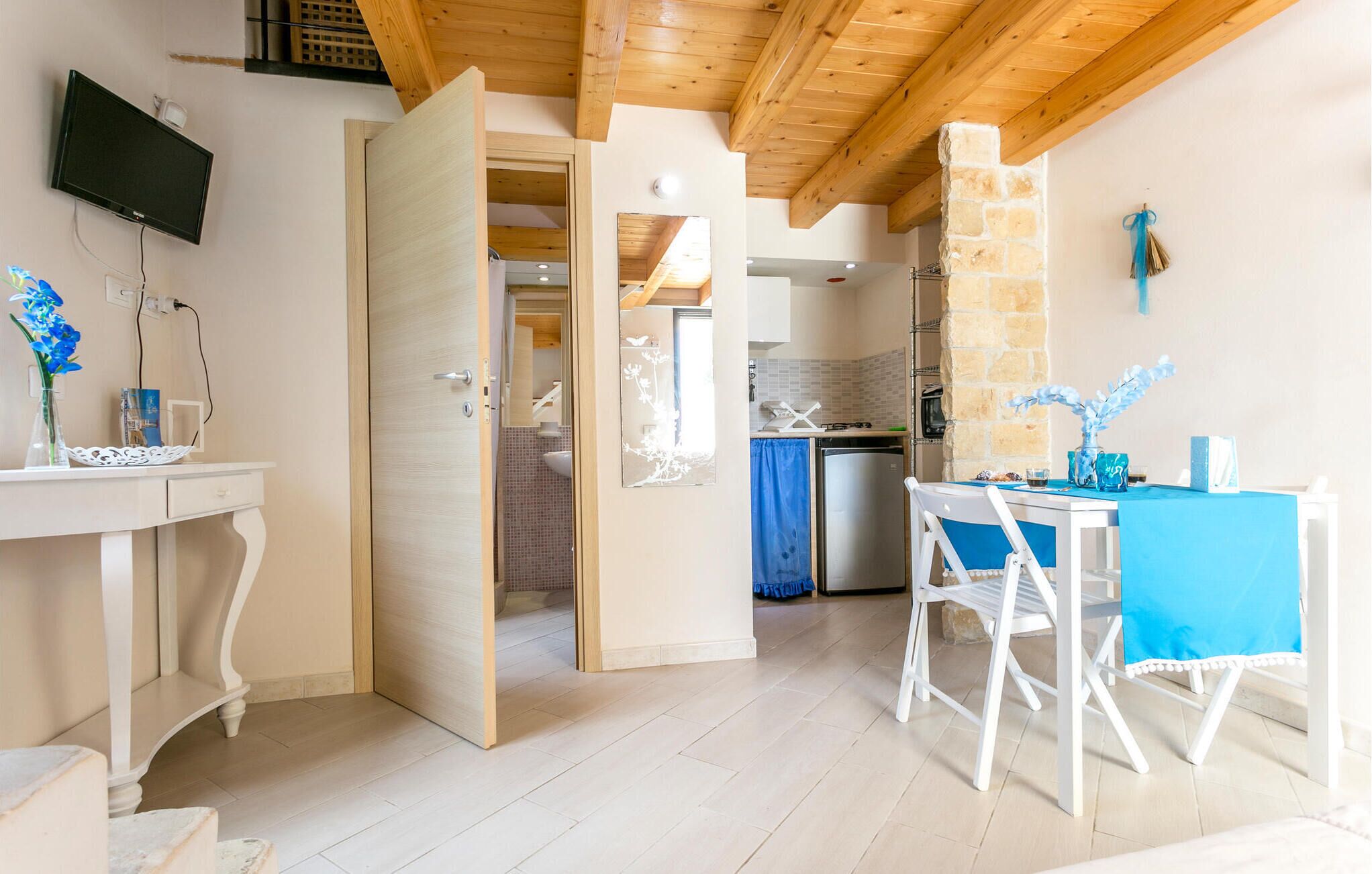 Una cocina moderna con una pared de piedra, un área de comedor con mantel azul y un televisor montado en la pared.
