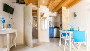 A modern kitchen with a stone wall, a dining area with a blue tablecloth, and a TV mounted on the wall.