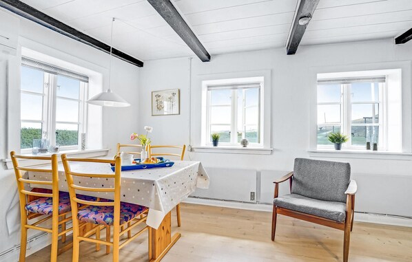 A dining area with a table set for two, wooden chairs, and a grey sofa.