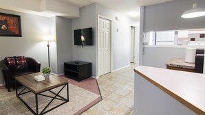 Un salon moderne avec une table basse, un canapé noir, une lampe et un téléviseur fixé au mur.
