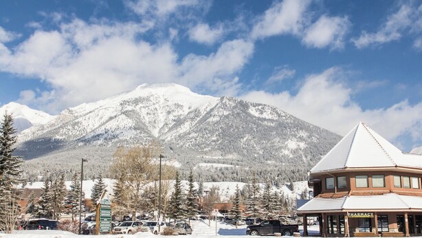 Une montagne enneigée, avec un bâtiment de pharmacie au premier plan.