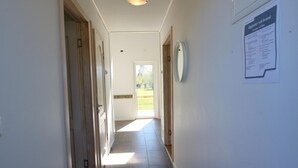 A hallway with wooden doors, a tiled floor, and a door leading outside. There is a wall-mounted clock and a notice board with text. - Beautiful home in Löttorp with WiFi (Löttorp)