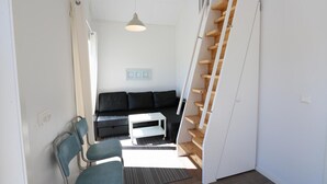 A compact living space with a black sofa, a white coffee table, and a staircase with wooden steps. - Beautiful home in Löttorp with WiFi (Löttorp)
