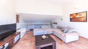 A spacious living area with a large sofa set, a flat-screen TV, and a coffee table.