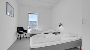 A minimalist bedroom with a bed, a chair, a desk, and a window.