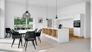 A modern kitchen with white cabinets, a central island, and pendant lighting.