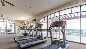 A gym with treadmills, exercise bikes, and a large window overlooking a balcony.