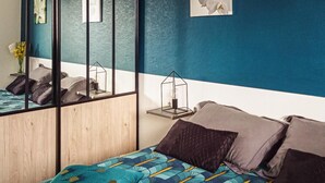 Camera da letto con un letto, cuscini, un comodino, uno specchio e una lampada a parete.