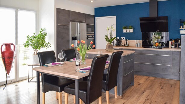 Una cucina moderna con una parete blu a contrasto, un forno integrato e una cappa aspirante nera.