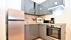 Una cucina compatta con frigorifero, microonde, tostapane, macchina del caffè e forno.