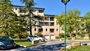 Un edificio residenziale a più piani con balconi, un'area di parcheggio e un lampione.