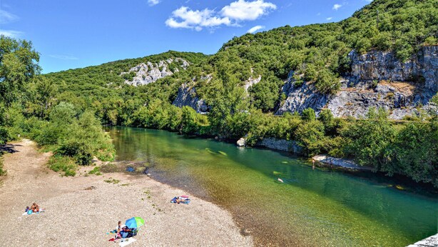 Un fiume circondato da vegetazione lussureggiante e ripidi pendii rocciosi.