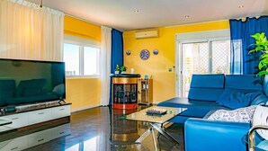 Una sala de estar moderna con una televisión de pantalla plana, un sofá, una mesa de centro y una chimenea pequeña.