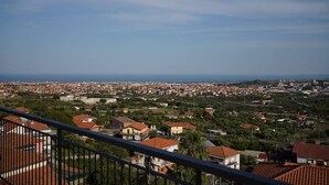 A panoramic view of a coastal cityscape with a mix of residential and commercial buildings, a clear sky, and a distant view of the sea. - Holiday flower villa with pool (Misterbianco)