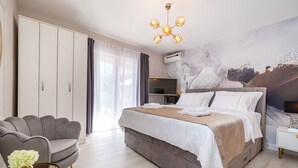 A modern hotel room with a large bed, a grey armchair, a flat-screen TV, and a ceiling light fixture. - Beautiful home in Zaton (Zaton)