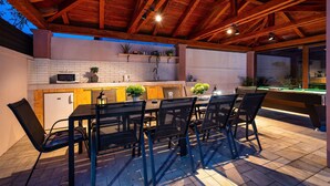 An outdoor kitchen area with a dining table and chairs, a pool table, and a brick wall. - Beautiful home in Zaton (Zaton)