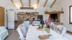 A dining area with a table set for four, a kitchen with a stone backsplash, and a fireplace. - Pet friendly home in Kostrcani with WiFi (Kostrcani)