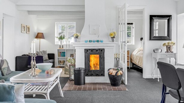 A modern living room with a fireplace, a sofa, a coffee table, and a dining area. - 3 bedroom gorgeous home in Ebeltoft (Ebeltoft)