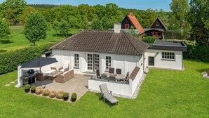 A large white house with a tiled roof, a patio with outdoor furniture, and a well-maintained lawn. - 3 bedroom gorgeous home in Ebeltoft (Ebeltoft)