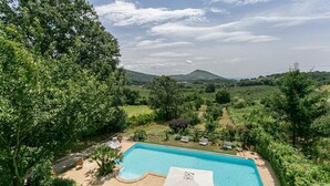 A rectangular swimming pool with a tiled deck, surrounded by lush greenery and trees. - Nice home in Bassano Romano with WiFi (Bassano Romano)