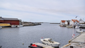 A harbor with boats docked, a red building, and white houses with red roofs.