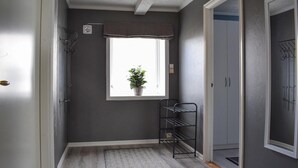 A hallway with a window, a potted plant, a metal rack, and a wardrobe.