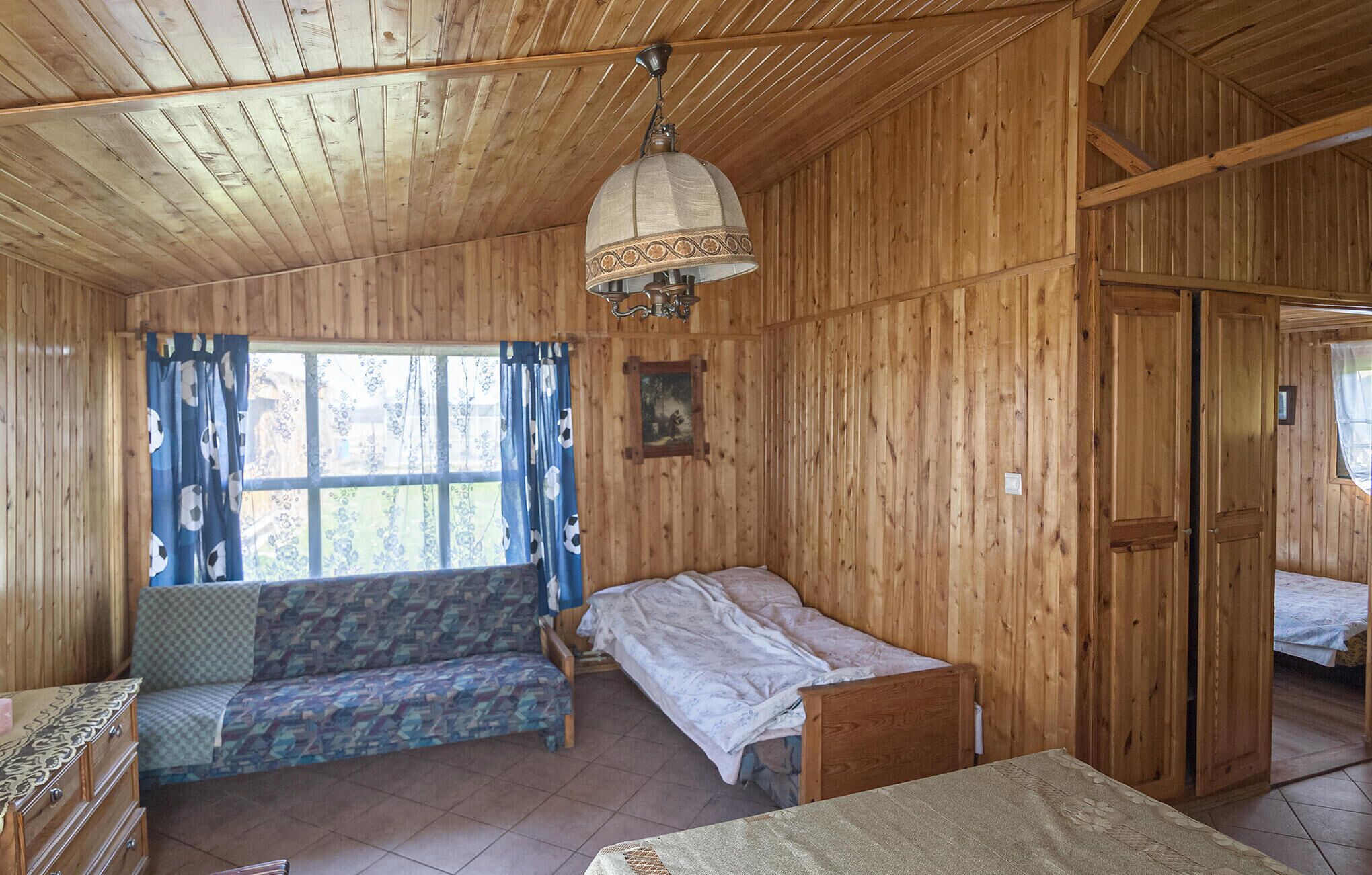 A wooden cabin room with a bed, a sofa, a small table, and a wardrobe.