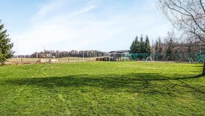 A grassy field with a playground and a building in the background.