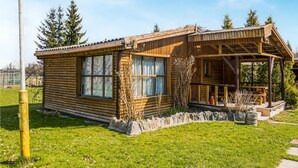 A wooden cabin with a porch and a stone foundation.