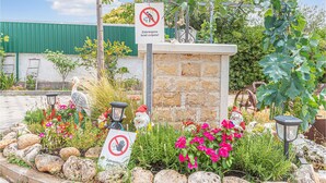 A garden with a stone wall, a sign prohibiting dogs, and various plants and flowers.