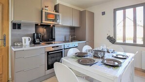 Een moderne keuken met een eethoek, inclusief een magnetron, koffiezetapparaat en een eettafel gedekt voor vier personen.