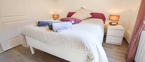 A neatly arranged bedroom with a bed, bedside tables, and a nightstand.