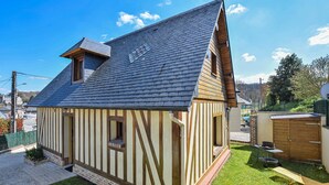 Een klein, laag huis met een steil dak, een duidelijke schoorsteen en een klein raam.
