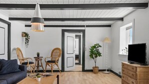 A modern living room with a sofa, chairs, a coffee table, a TV, and a bookshelf. - Nice apartment in Ulfborg with WiFi (Ulfborg)