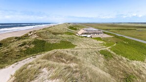 A coastal building with a thatched roof, surrounded by grassy dunes and a beach. - Nice apartment in Ulfborg with WiFi (Ulfborg)