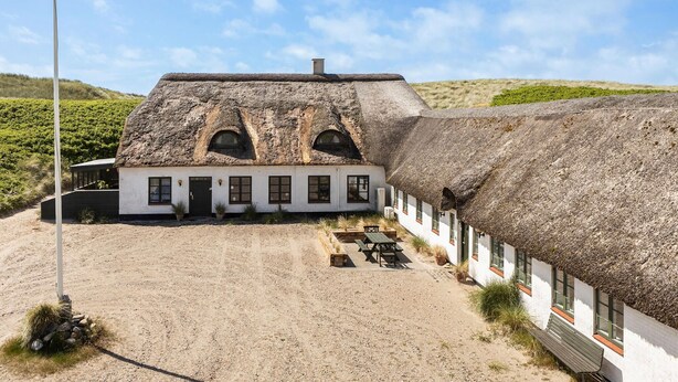 A thatched-roof building with a white exterior, a gravel driveway, and a flagpole. - Nice apartment in Ulfborg with WiFi (Ulfborg)