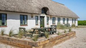 A thatched-roof building with a white facade, a green door, and a table with chairs outside. - Nice apartment in Ulfborg with WiFi (Ulfborg)