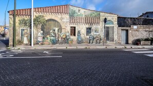 Un edificio con un murale raffigurante una scena di strada, un tetto in tegole e un cartello che indica un'attività commerciale.