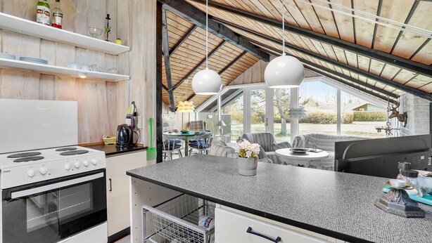 Una cocina moderna con estufa, horno y comedor con mesa y sillas.